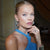 Elegant blonde model wearing a blue dress with a sleek tight bun, glowing skin, and soft nude bridal-style makeup