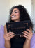 gorgeous client with curly hair smiling brightly while looking at her warm bronzed glam makeup look in a compact mirror by Karysha Beauty