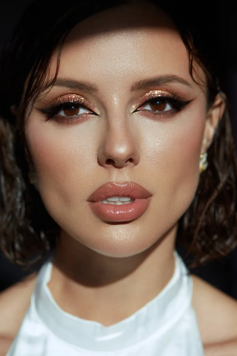 Close-up of a person with dramatic makeup and a white top.