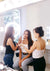 Two women in a beauty salon with one applying makeup to another.