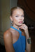 elegant blonde woman with blue eyes in a halter blue dress showcasing fresh-faced natural glam makeup, sleek bun hairstyle