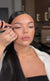 Makeup artist applying eyeliner to a model's upper lash line.