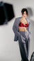 Karysha wearing a red satin top and gray suit against a neutral background