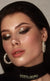 Dark smoky eye makeup with gold shimmer, bronzed cheeks, and glossy lips