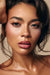 Model showcasing sun-kissed dewy glam makeup with faux freckles, subtle winged eyeliner, and glossy lips styled by a Miami makeup artist and hair stylist